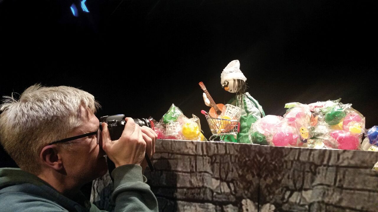 Ein Mann macht mit einer Kamera ein Foto von einer Handpuppe.