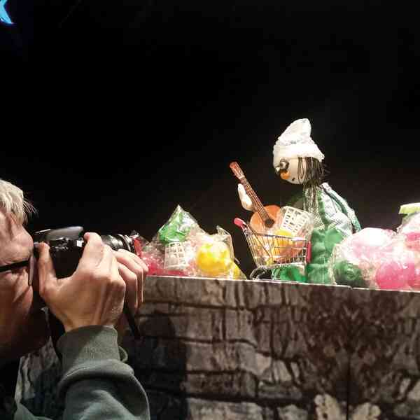Ein Mann macht mit einer Kamera ein Foto von einer Handpuppe.